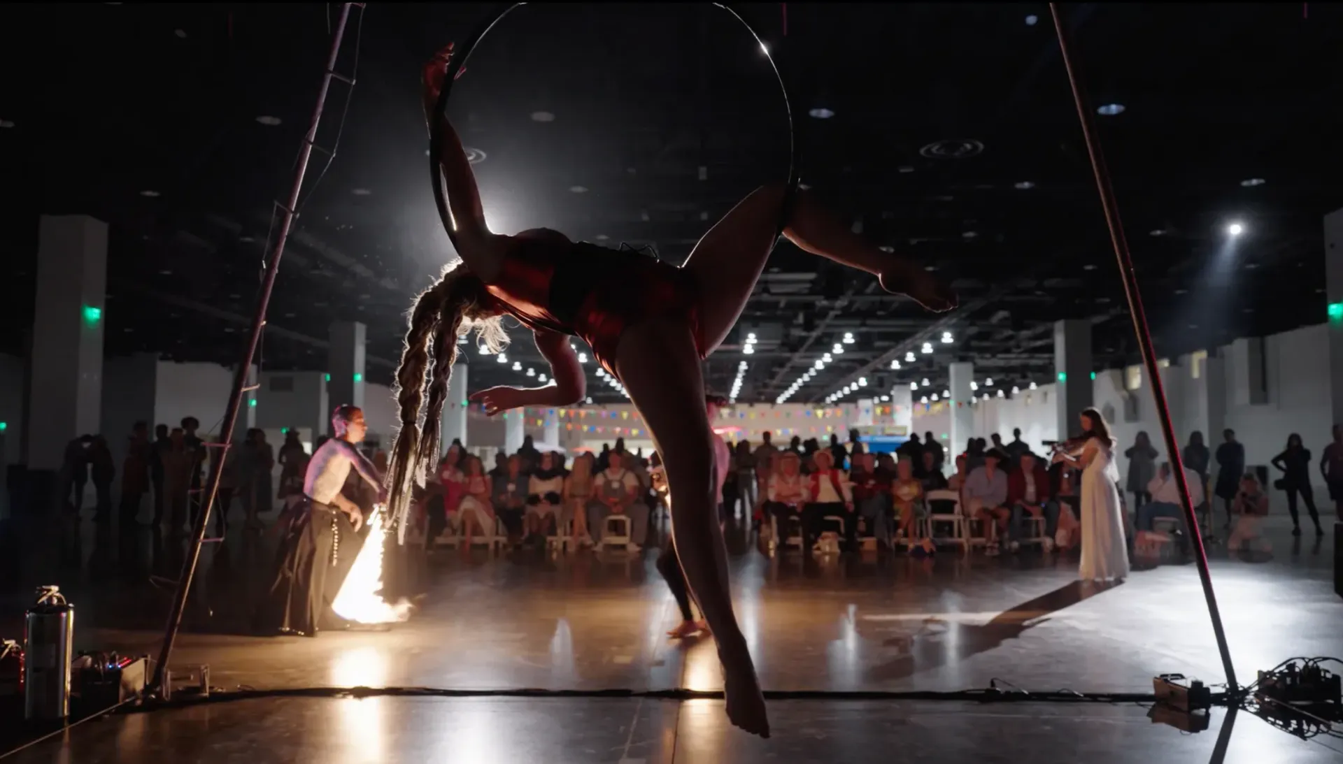 A woman is performing aerial acrobatics in front of a crowd.