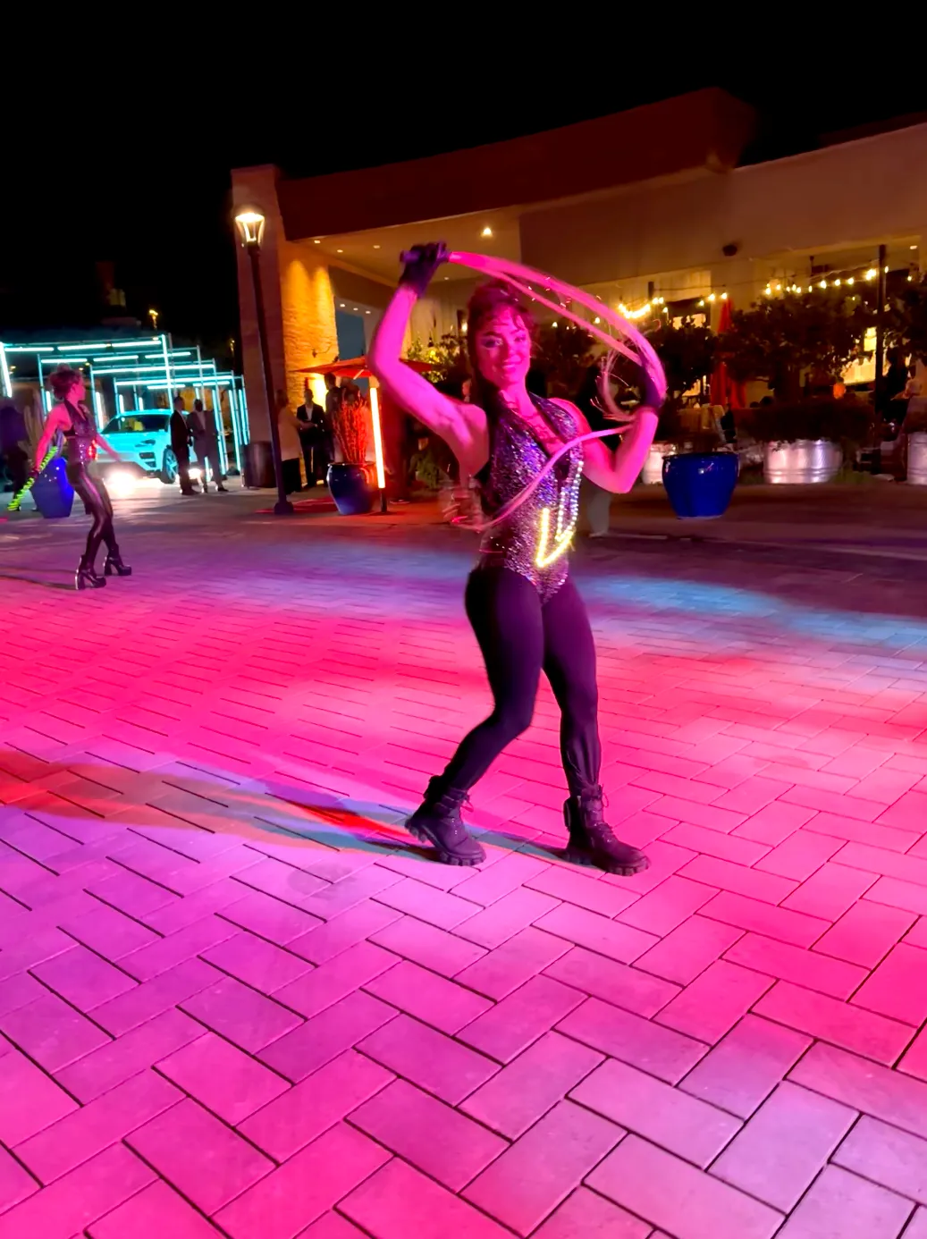 A woman is standing on a brick floor holding a hula hoop.