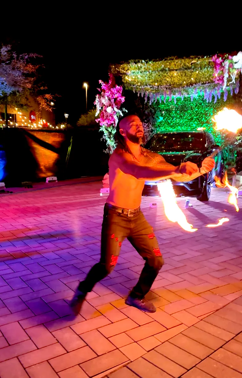 A shirtless man is holding a fire stick in his hands.