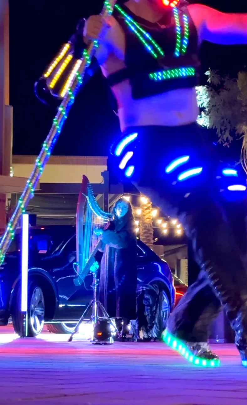 A man is playing a harp on a stage at night.