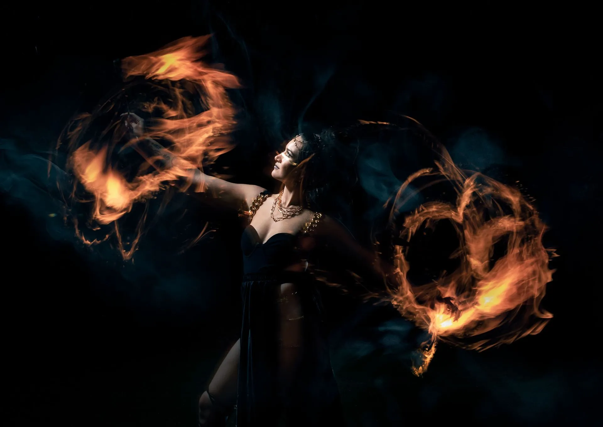 A woman is dancing with fire in her hands in the dark.