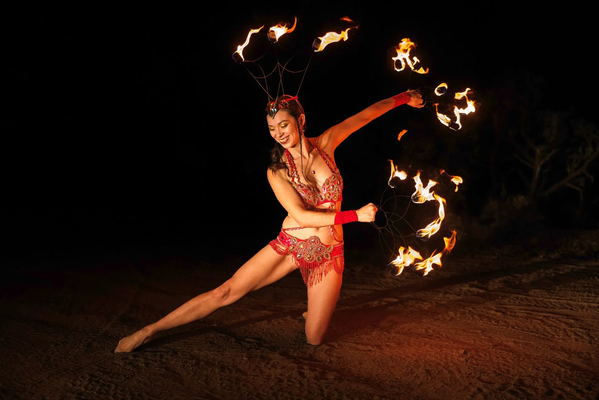 A woman in a costume is holding a stick of fire.