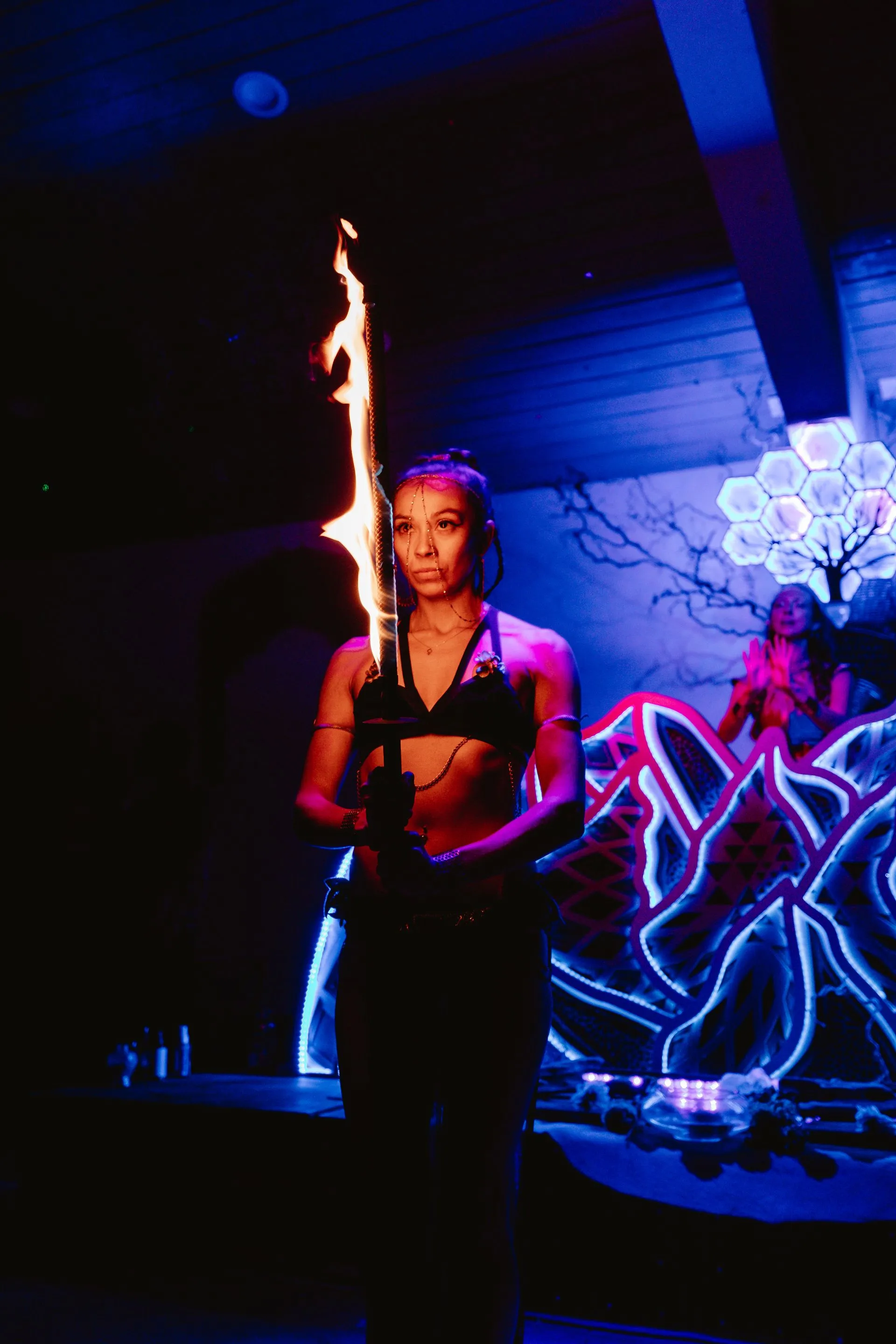 A woman is holding a torch in her hand in a dark room.