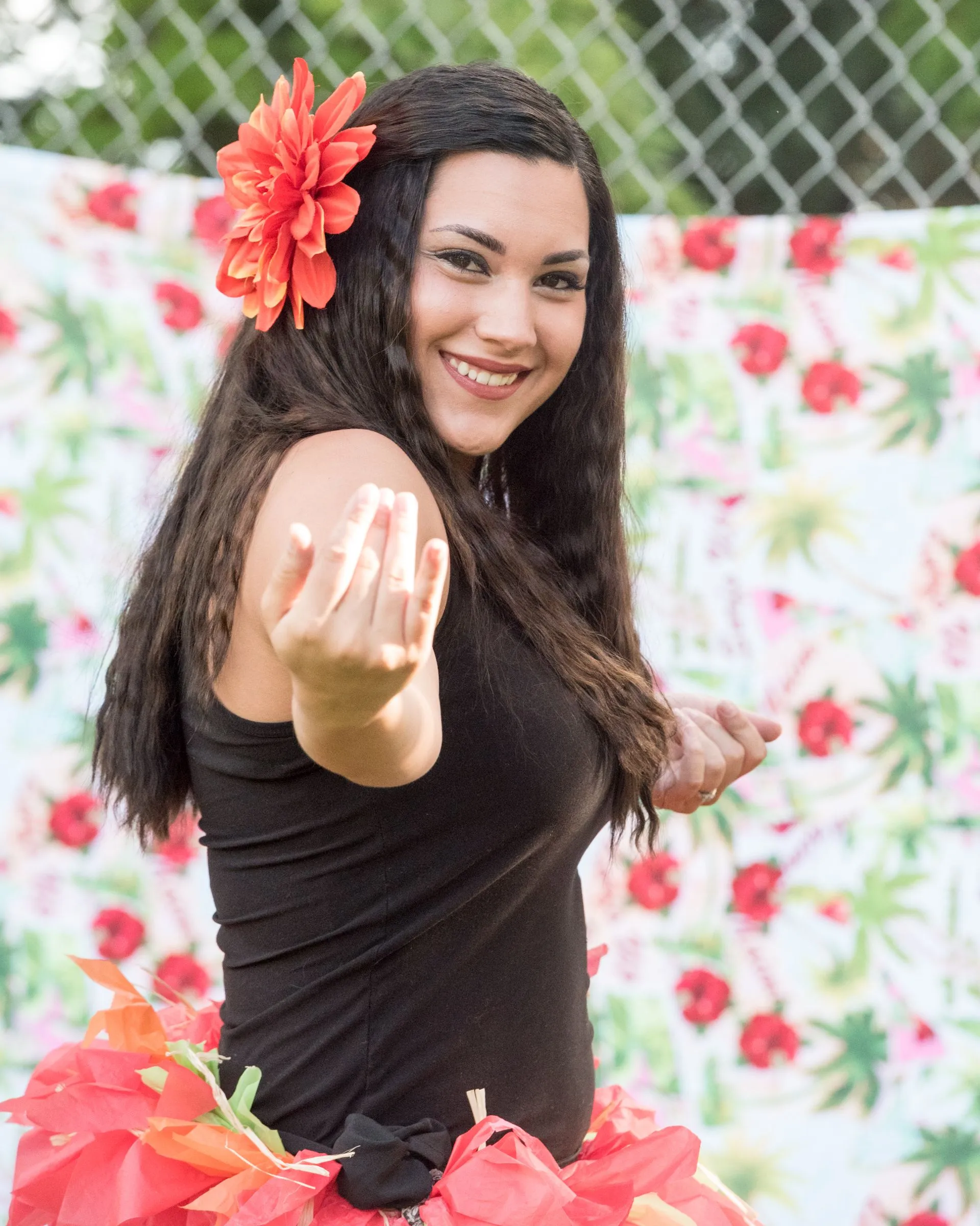A woman with a flower in her hair is pointing at the camera