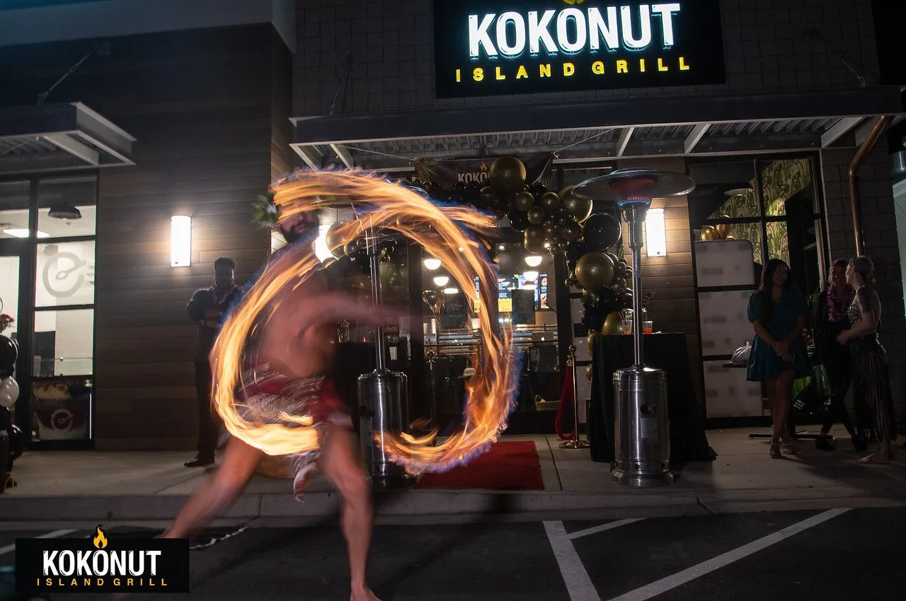 A man is playing with fire in front of a kokonut restaurant