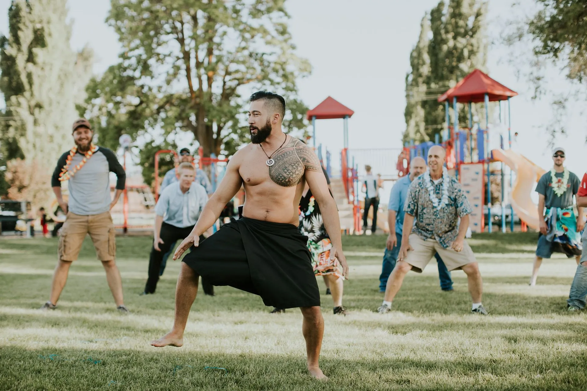 A group of men are dancing in a park.