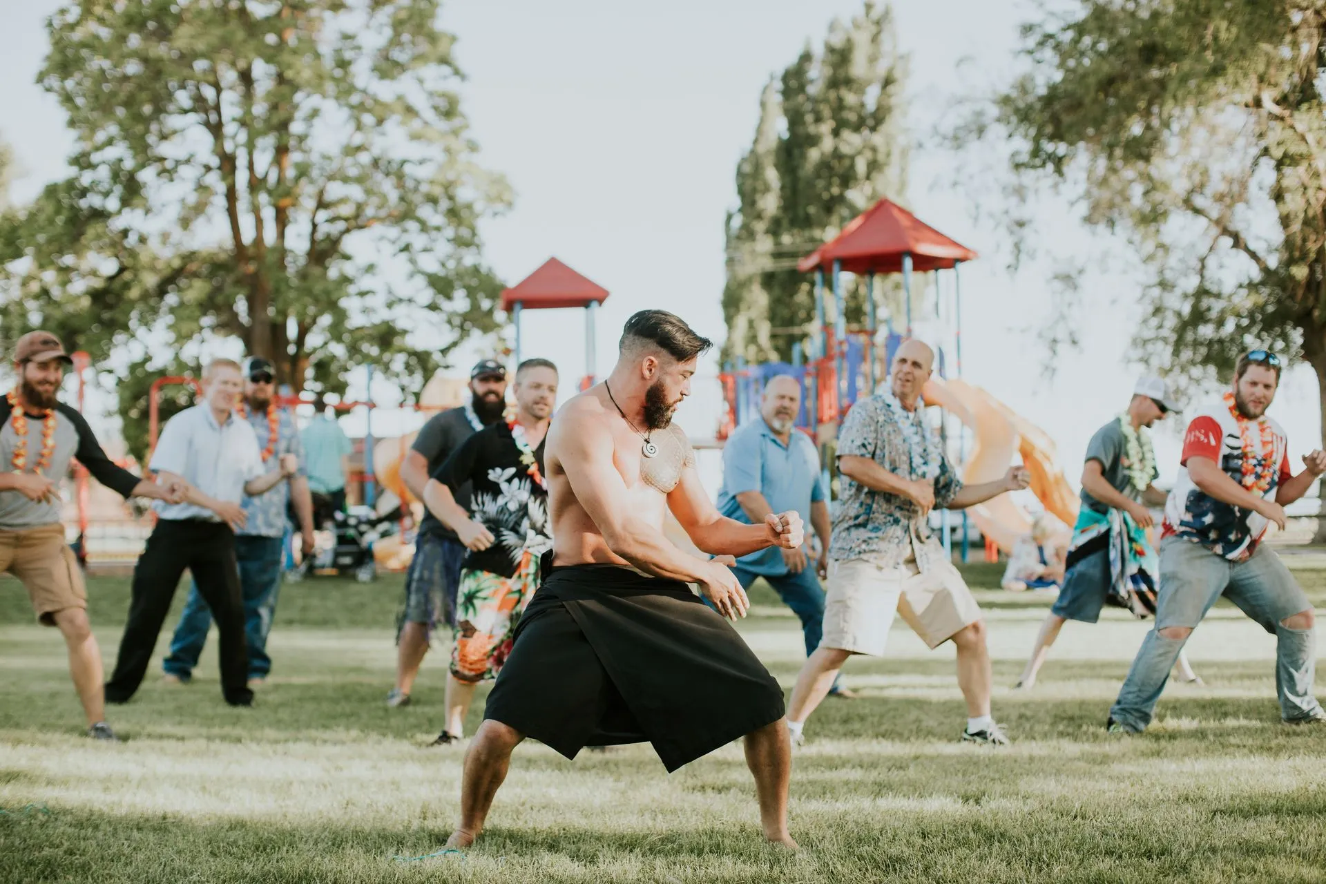 A group of men are dancing in a park.