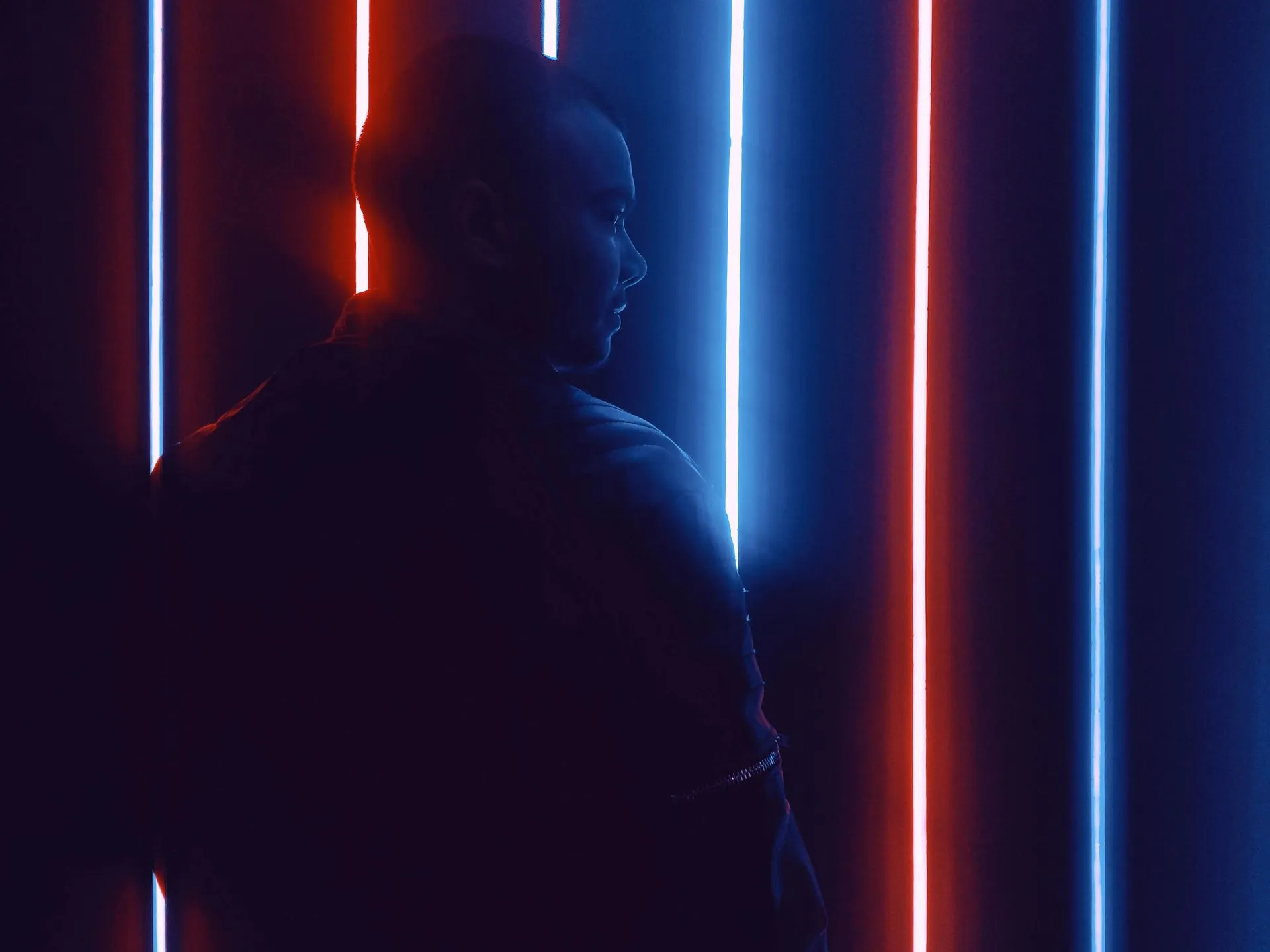 Person in silhouette against neon blue and red light strips.