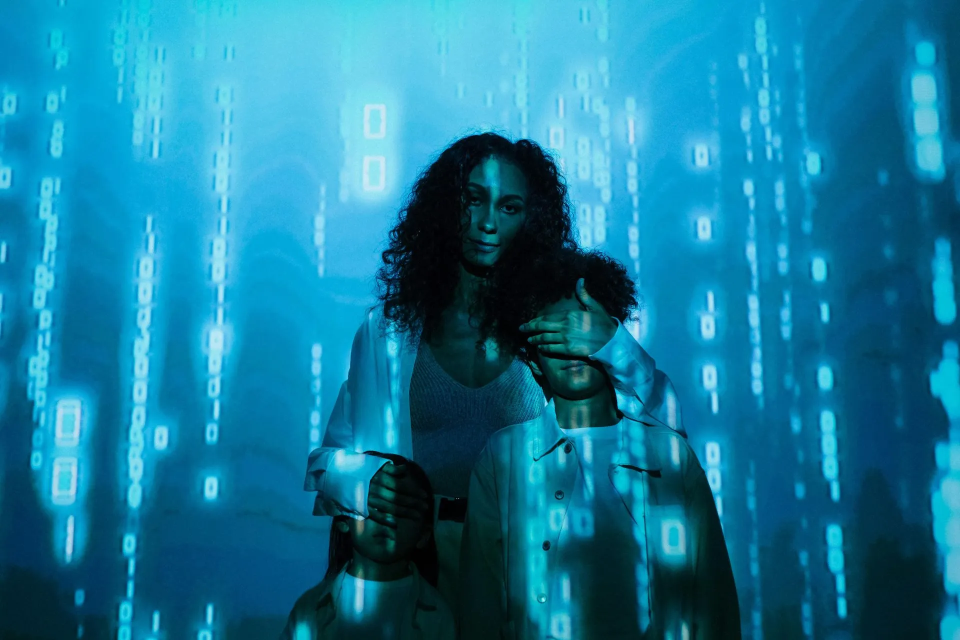 Woman and child embrace in a blue, digitally projected environment of falling binary code.
