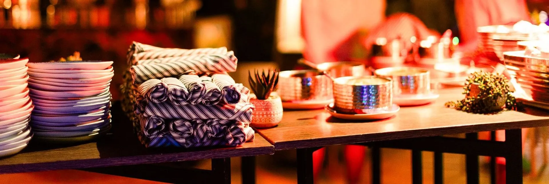 Stacked striped napkins and place settings on candlelit table with candles and glassware